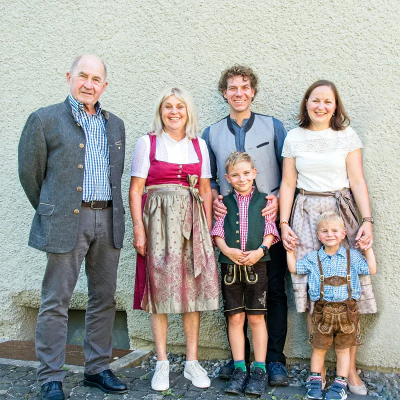 Familienbild mit fünf Personen in traditioneller Tracht vor hellgrauem Hintergrund