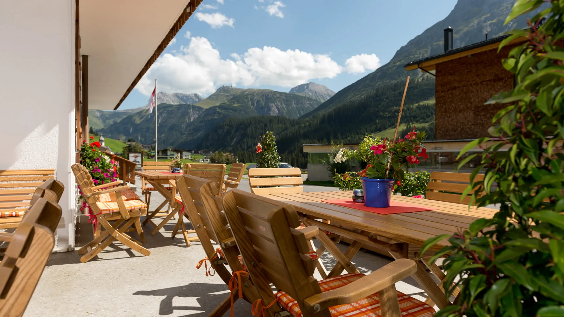 Terrasse mit Holztischen und Stühlen, Berglandschaft im Hintergrund