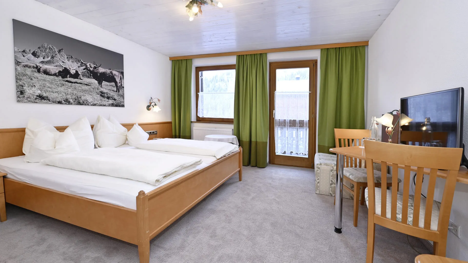 Gemütliches Hotelzimmer mit Doppelbett, Schreibtisch und Vorhängen