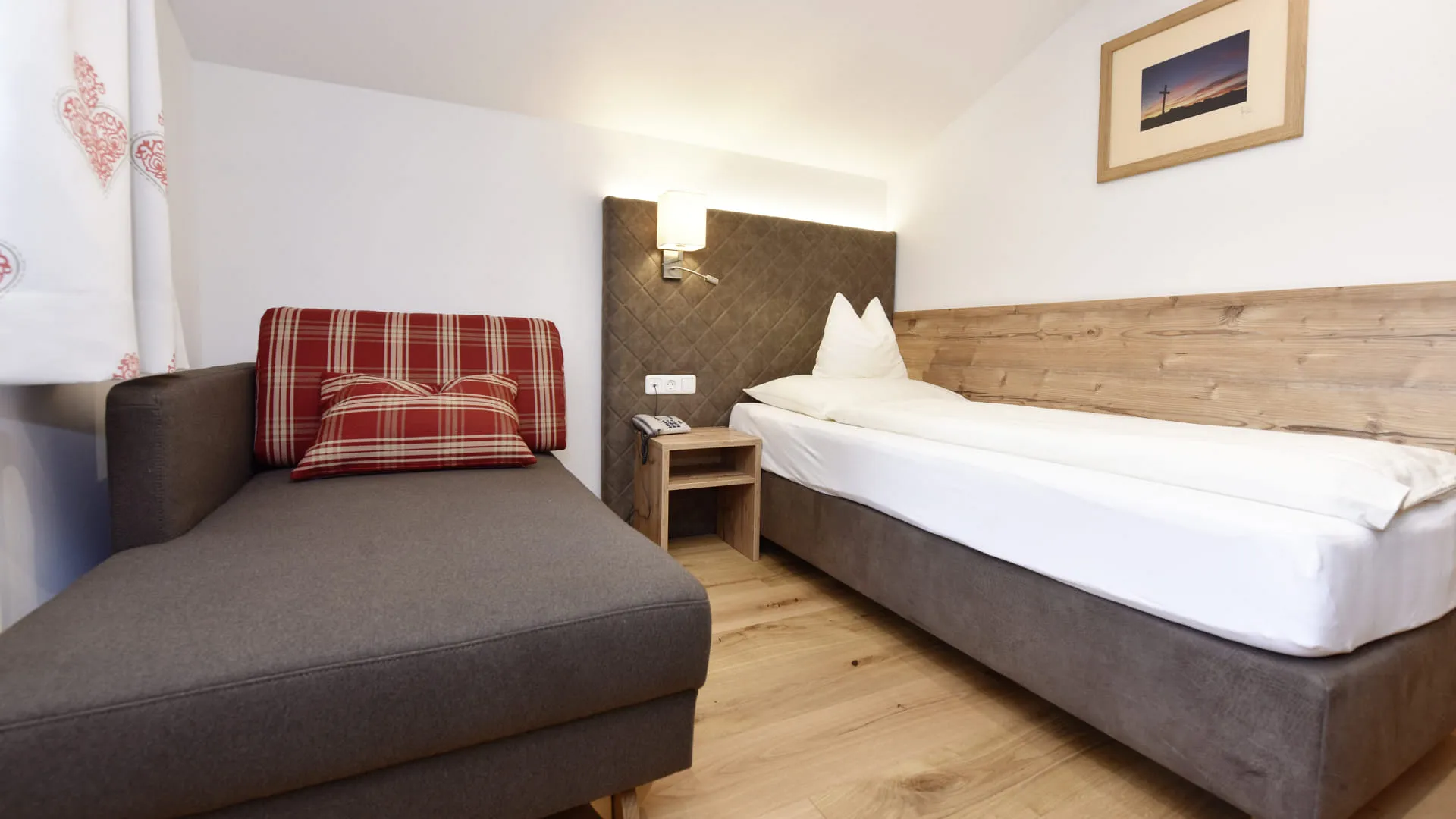 Helles Zimmer mit einem Bett, einer Couch und einem kleinen Tisch.