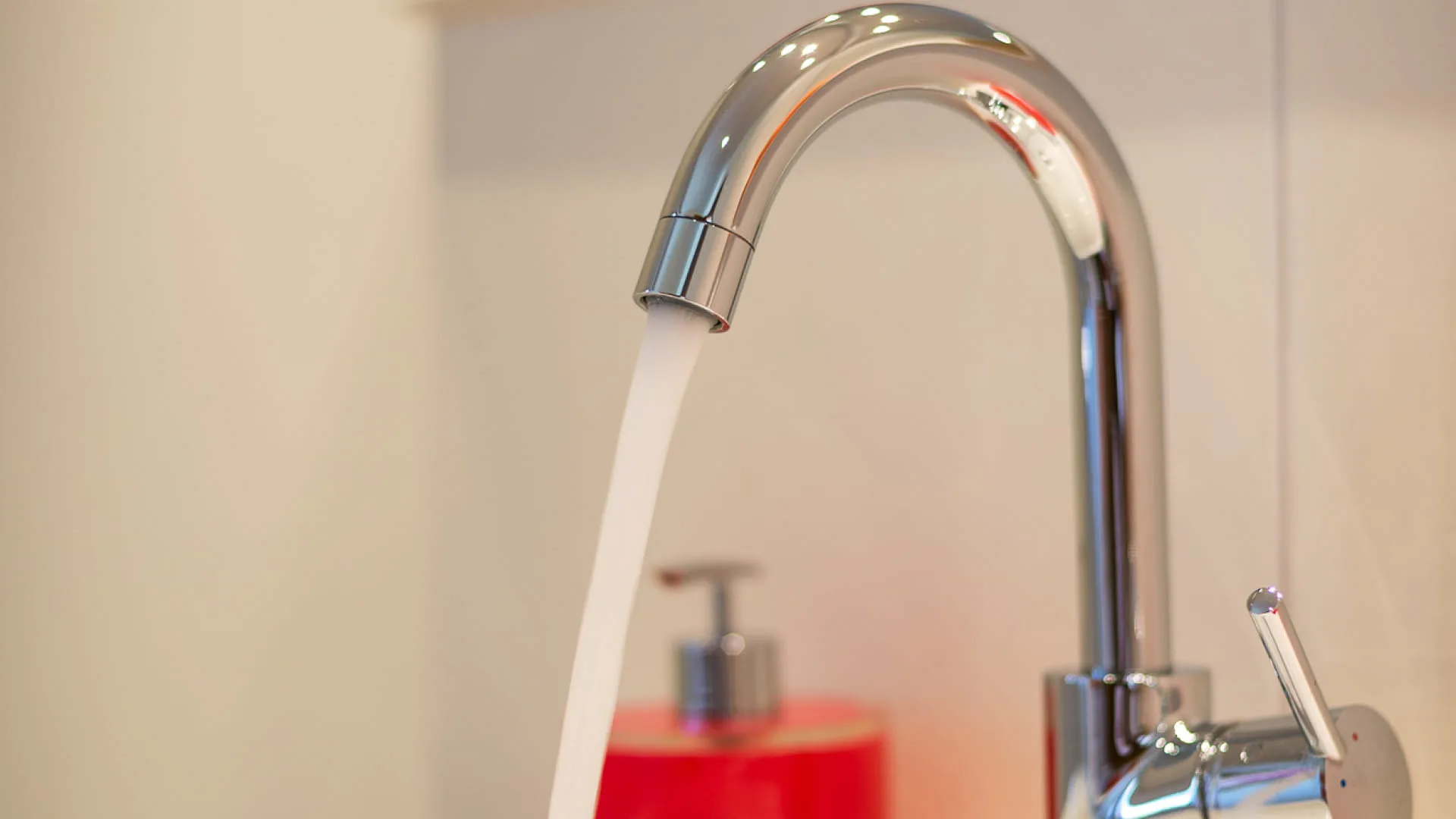 Moderne Wasserhahn mit fließendem Wasser über einem Waschbecken