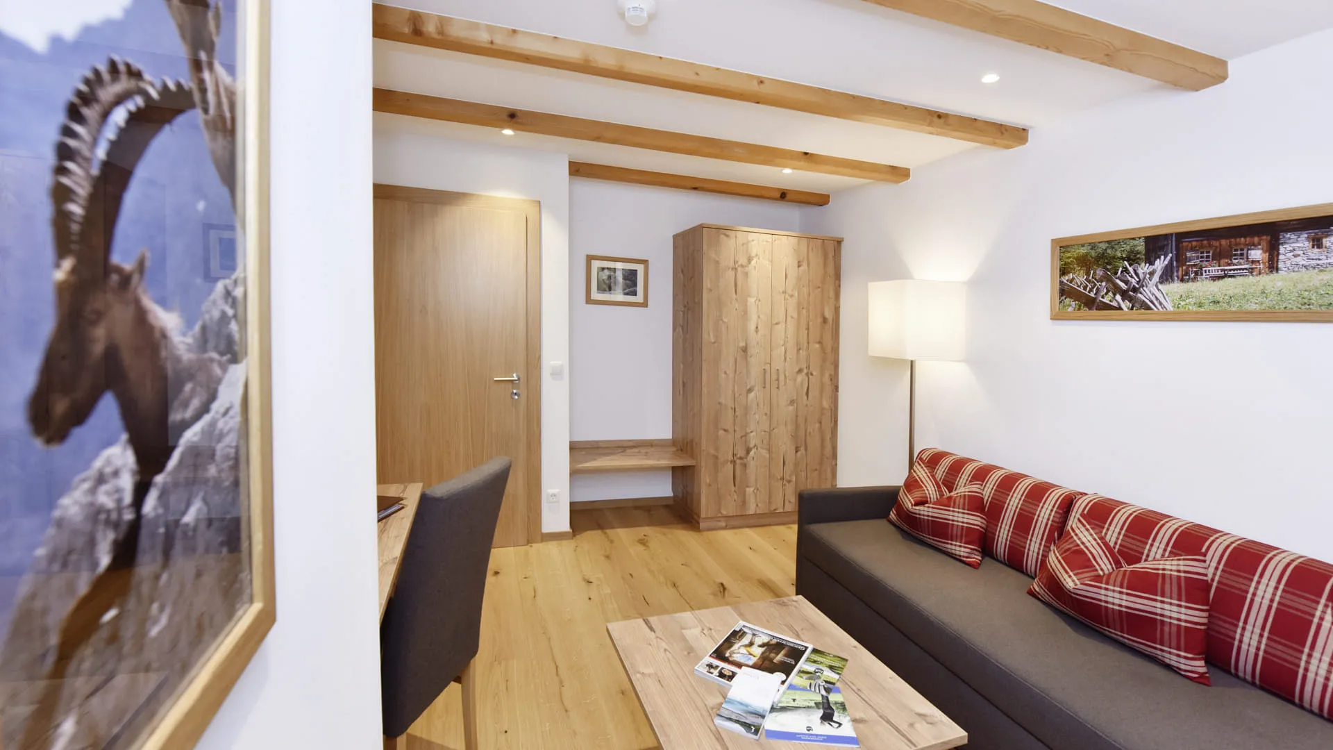 Moderne Wohnraum mit hölzernen Balken, Sofa und Bilderrahmen.